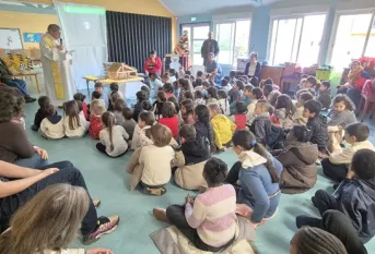 des enfants assis devant un prêtre lors d'une célébration de Noël