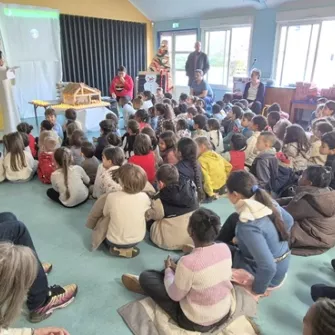 des enfants assis devant un prêtre lors d'une célébration de Noël